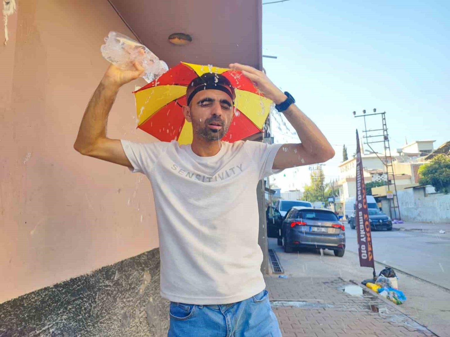 asiri-sicaklar-nedeniyle-kafasina-taktigi-semsiye-ile-geziyor